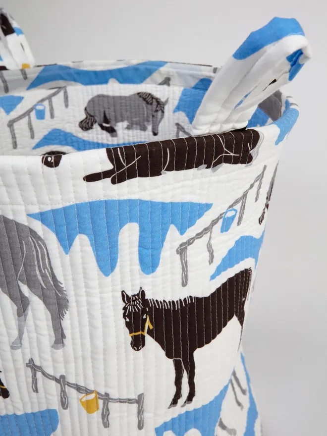 Horse Ranch Quilted Storage Basket detail of stitching, sitting against a grey backdrop.