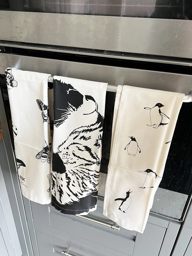 Insects tea towel folded on over the oven handle with two other tea towels