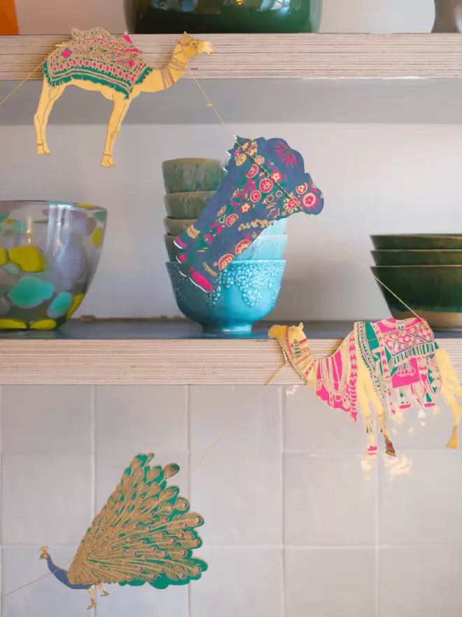 Gold embellished camels, elephants and peacock hanging on shelves with bright bowls