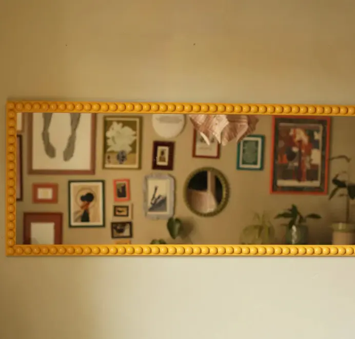 Floor-length bobbin mirror with a decorative turned-wood frame, placed in a classically decorated room with elegant furnishings.