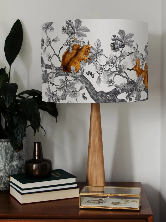 A decorative lampshade featuring red squirrels among oak leaves and acorns, inspired by the British countryside and woodland wildlife.