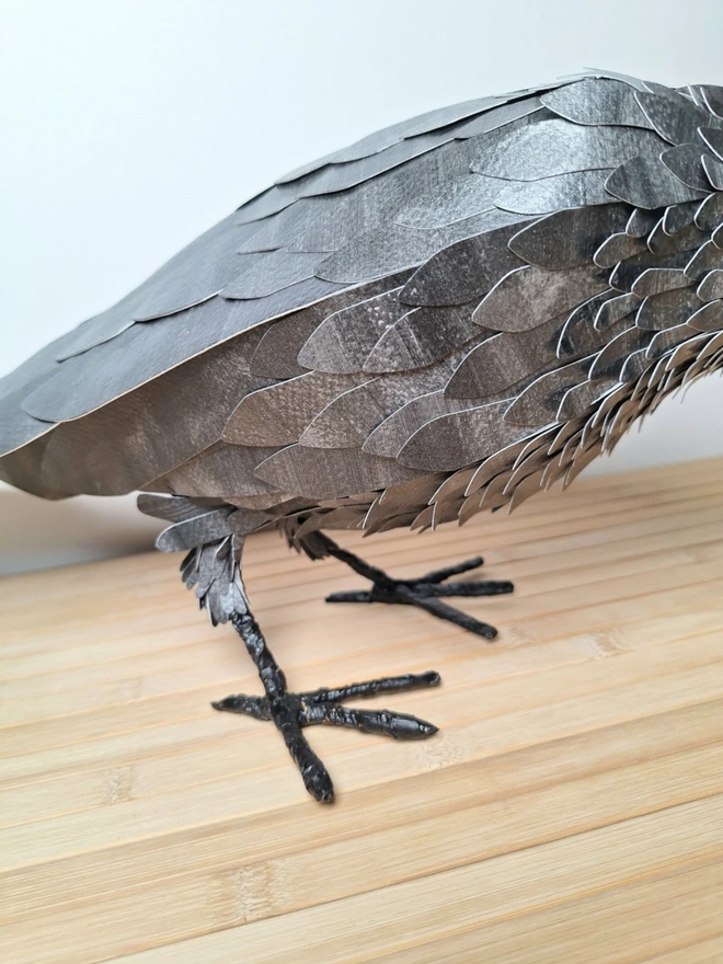 close up of the handprinted and hand cut feathers covering the body of the raven sculpture