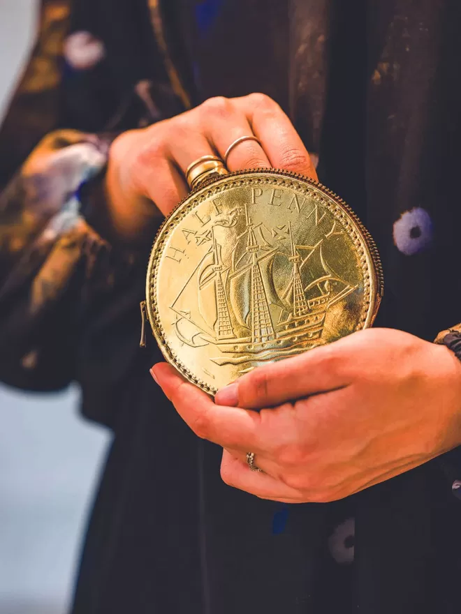 Fun Sized Gold Leather Half Penny Purse seen held by someone wearing a black top.