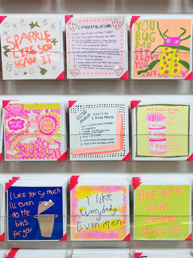 A new baby card with a list of funny instructions printed in fluro orange & deep blue on a rack