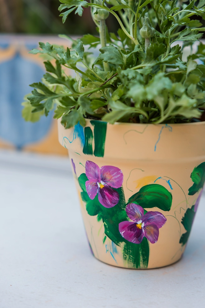 hand painted terrecotta floral plant pot background in a pale yellow with pink and white blossom flowers