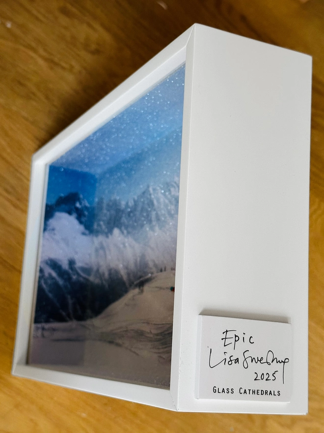 Miniature scene in an artbox showing a tiny snowboarder cruising down a snowy mountainface