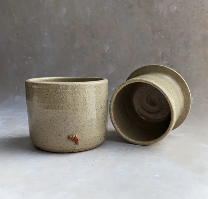 Croissant Butter Crock in biscuit glaze with a small croissant design on the front, set against a grey background.