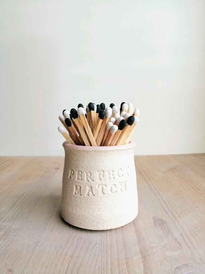 handmade match pot with black and white tip matches inside. 'Perfect Match' stamped on the outside of the pot