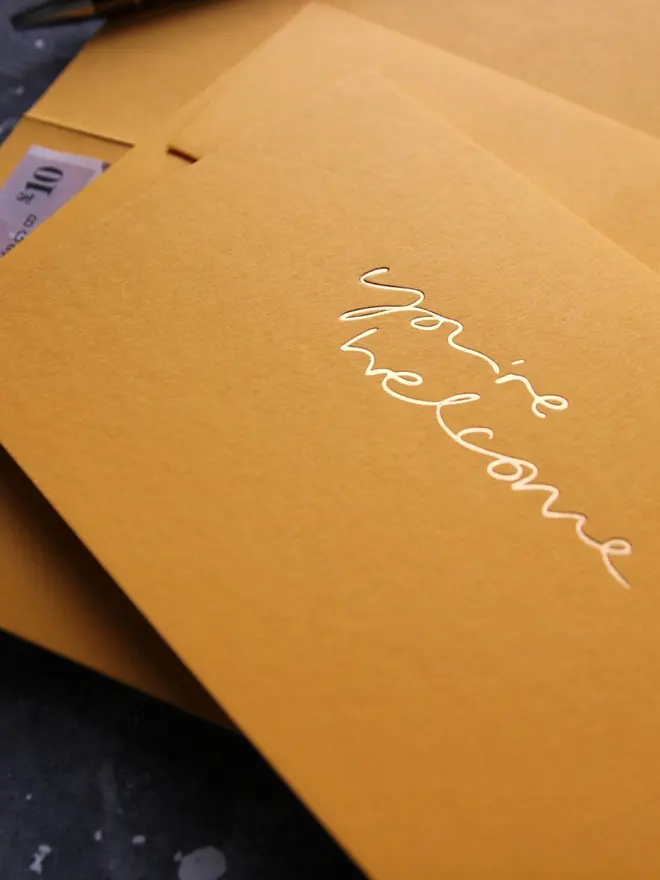 Hand foiled cash card or money wallet in a citrine colour in shiny gold foil text which says ‘you’re welcome’.