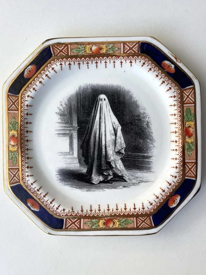 vintage plate with an ornate border, with a printed vintage illustration of a ghost in the middle 