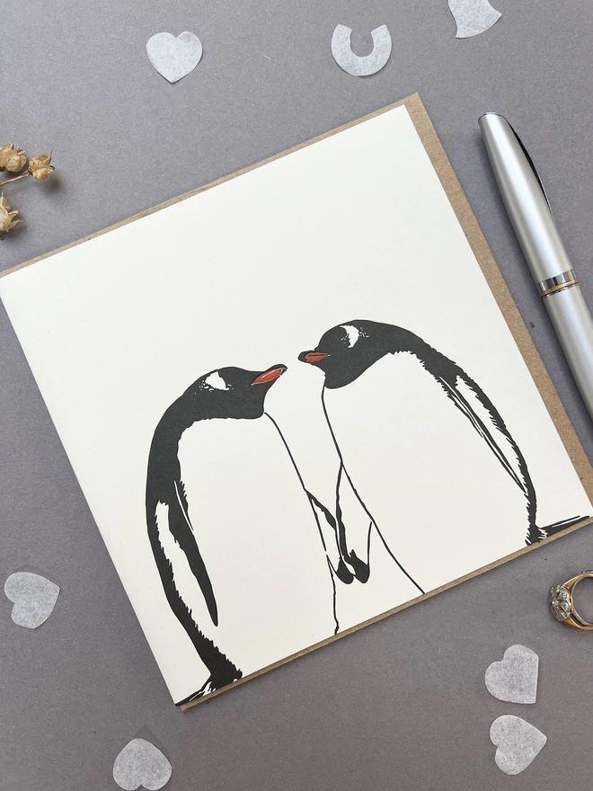 Gentoo penguin card with confetti, rings and a pen around it 