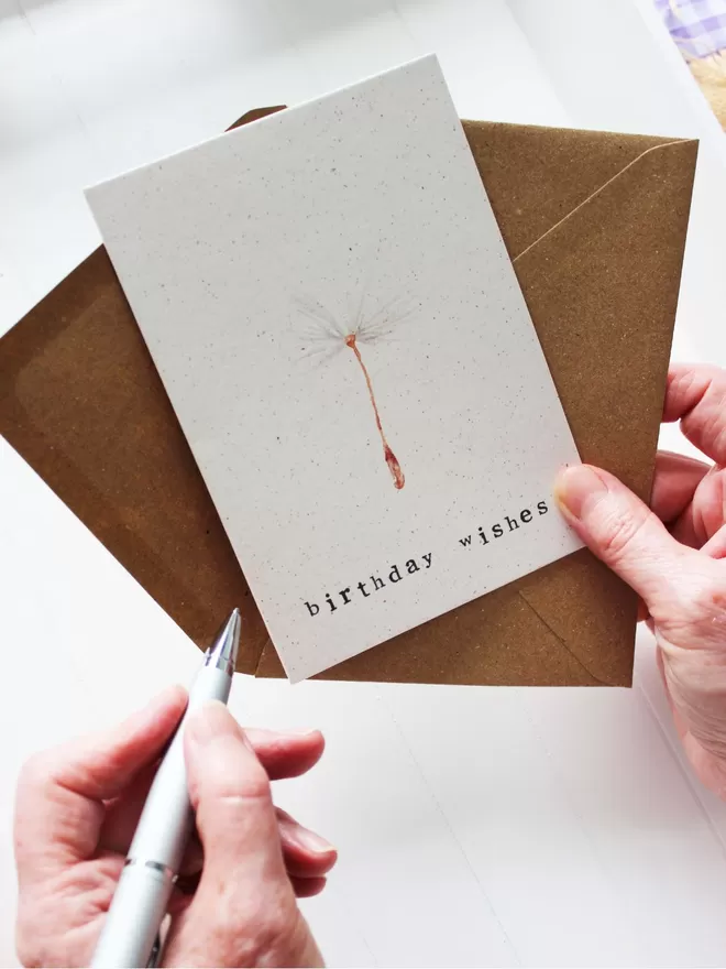 'Birthday Wishes' Card being help with pen ready to write inside