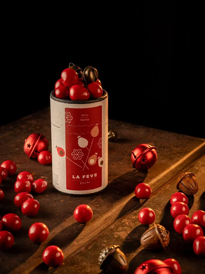 lifestyle shot of red chocolate tube packaging red chocolate balls scattered around