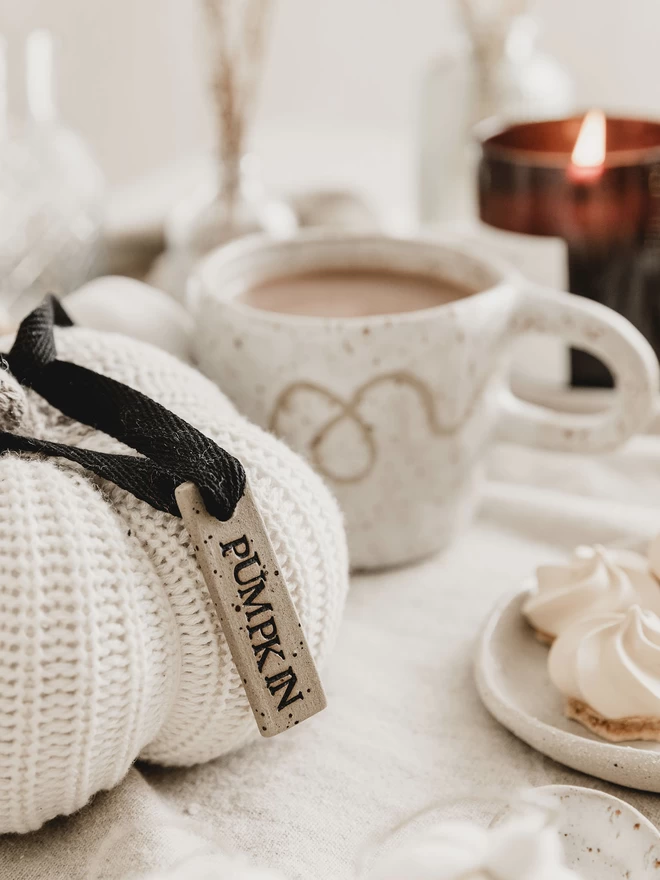 ceramic 'pumpkin' tag tied to a white knitted pumpkin