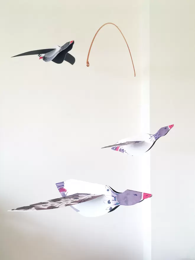 Esther Kent Three Geese illustrated paper mobile, hanging against a white wall.