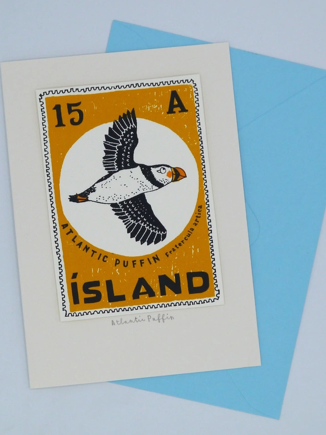 Bird Stamp Card Atlantic Puffin/ Iceland, a white card with a colourful bird design in the centre against a blue envelope on a white background. 