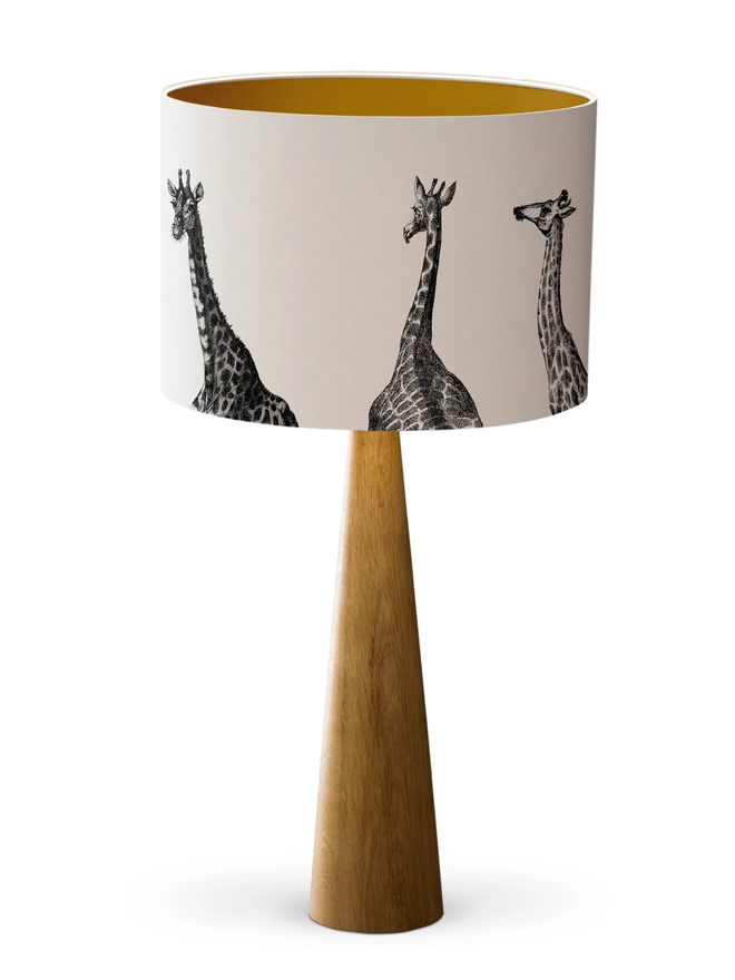Drum Lampshade featuring Giraffes with a gold inner on a wooden base on a white background