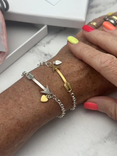 model wears sterling silver bracelet with gold arrow charm and small personalised silver heart charm