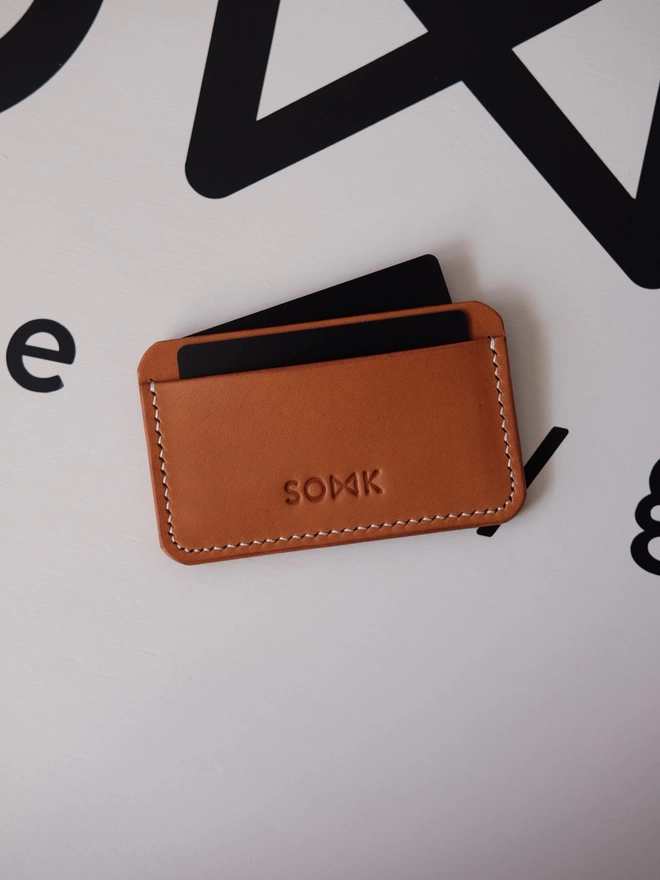 SOWK tan leather card holder seen with fake cards in it.