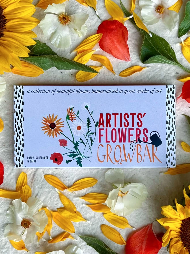 The Artists's Flowers Growbar surrounded by a display of yellow, red and white petals and flowers.