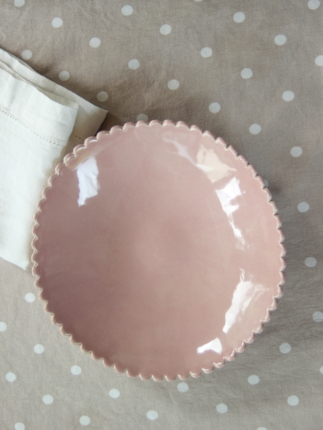 looking down on a pink scalloped edge serving bowl for salads or fruit bowl on a polka dot tablecloth