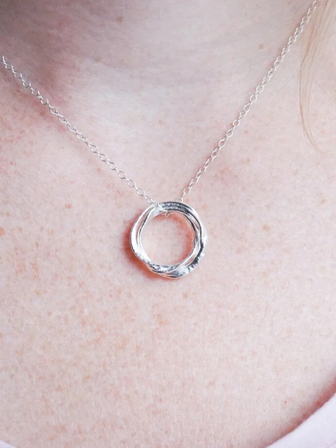 A woman wearing a Silver Entwined Circles Necklace