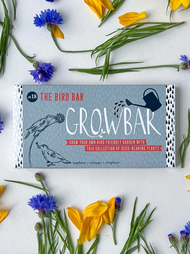 The Bird Growbar surrounded by yellow sunflower petals and blue cornflowers. 