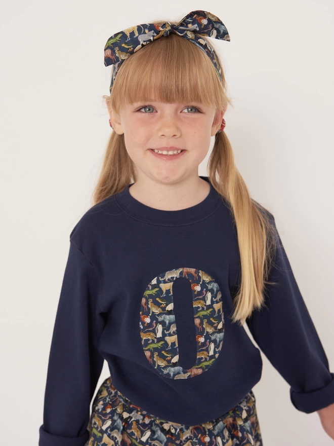 girl wearing a navy long sleeve tee with her initial on in Quey 2 Liberty print