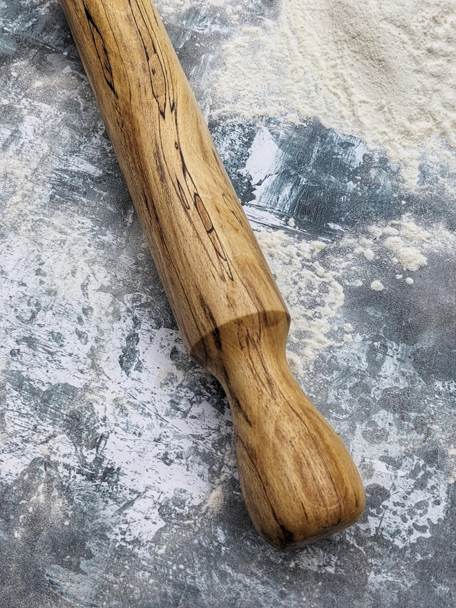 A close up of a stunning hand made rolling pin in Spalted Beech by Something From The Turnery. Displaying the all-natural detailing on the right hand side of the rolling pin. 