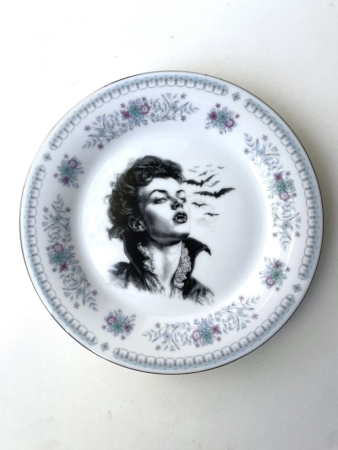 the vampire Lestat wtih bats behind him, the image is victorian in black and white and is printed directly onto an ornate vintage plate