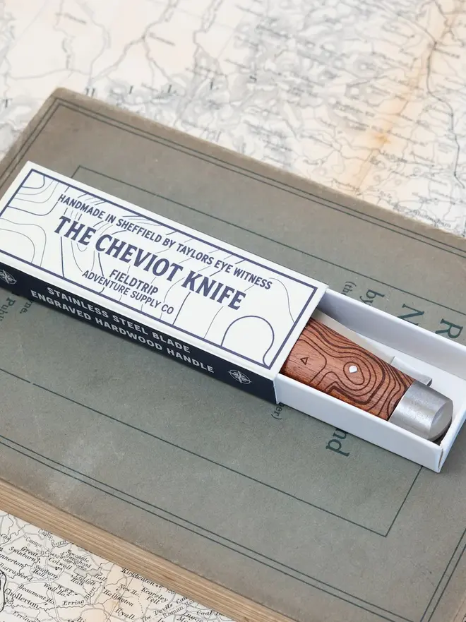 'the cheviot' folding pocket knife. a steel pocket knife with a brown wooden handle, folded up inside a gift box.