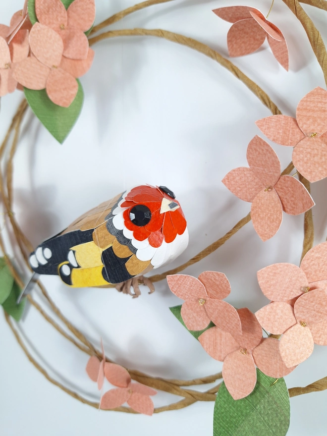 handmade goldfinch bird, sat on a wreath of paper hydrangea flowers