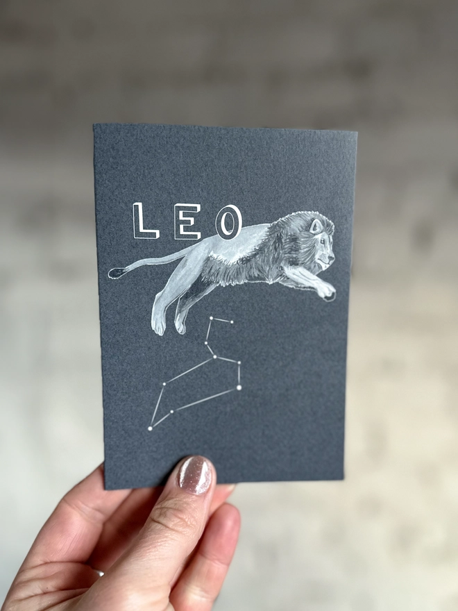 : a greetings card featuring a greyscale illustration of a zodiac style lion with the text “LEO”