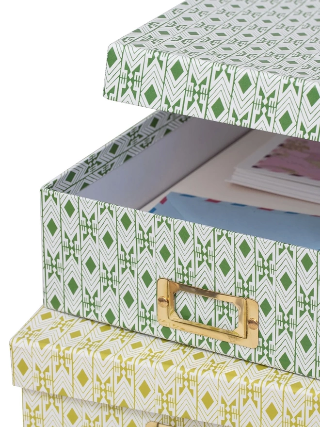 Tijan Lidded Portfolio Box, a collection of colourful portfolio boxes stacked on a plain surface. 