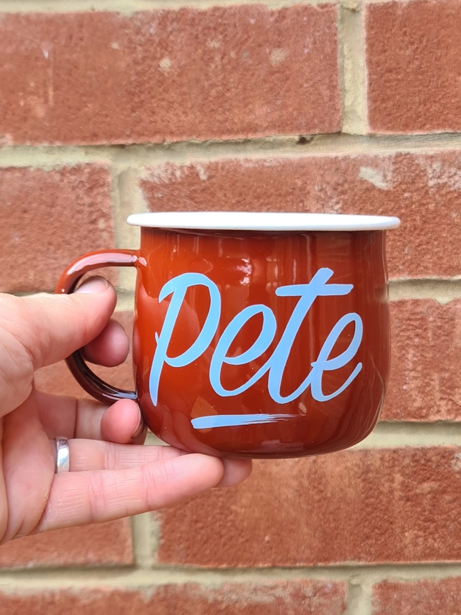 red enamel mug with pale blue 'pete' in sign writing style