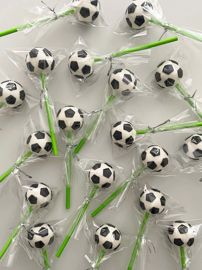 Football Cake Pops (Pack Of 6, 12, 18, 24), football cake pops in cellophane bags laid on a white surface.