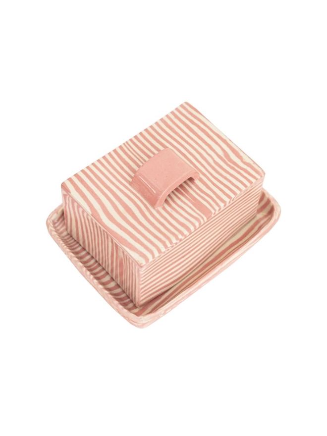 Striped Butter Dish, a colourful striped butter dish sitting on a white surface against a plain backdrop. 