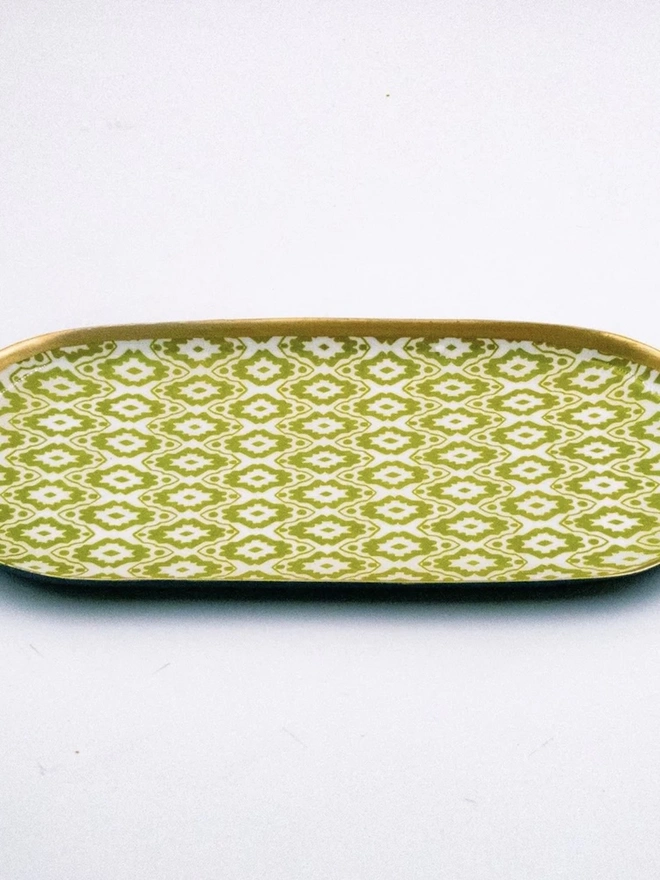 Perfect Enamel Oval Tray. An oval tray decorated with lime green and white geometric ikat-style print and finished with a gilded gold rim. The slim decorative tray is ideal for a dressing table, desk or bathroom shelf.