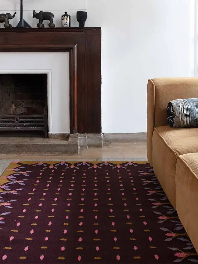 Hedgerow Flatweave Rug, a colourful rug sitting in a decorated room. It is accompanied by some household items.