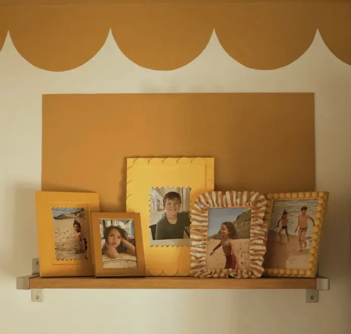 Multiple soft ruffled frames with striped fabric trim displayed on a cabinet. 