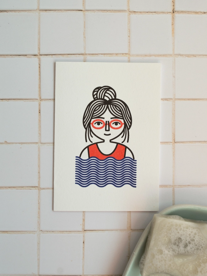 A cute little card illustrated with a graphic female swimmer in a red swimming costume on a white tiled background.