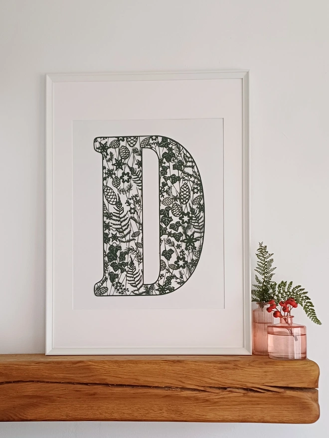 Framed Letter D papercut in Dark Green filled with winter plants, flowers and berries