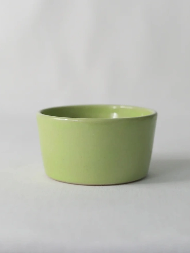 Classic Side Bowl, a colourful ceramic bowl on a wooden surface against a grey backdrop. 