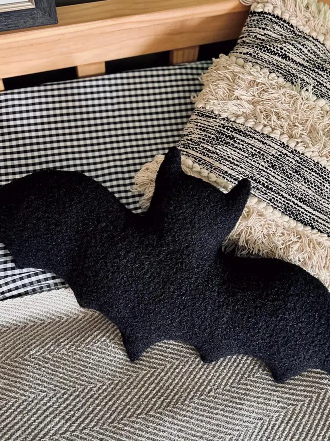 boucle bat pillow. a black cushion shaped like a bat.