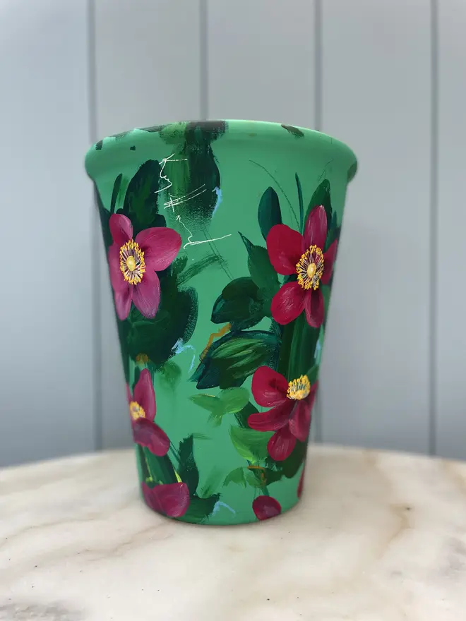 Unique hand-painted terracotta pot featuring deep pink anemone on a turquoise background