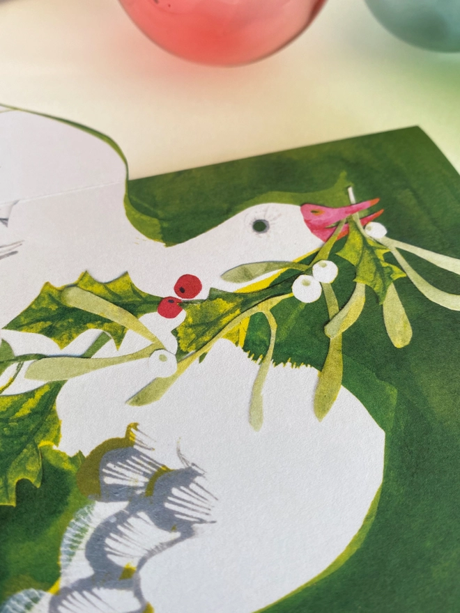 Esther Kent illustrated Christmas Card showing white goose on green inky background, carrying holly and mistletoe