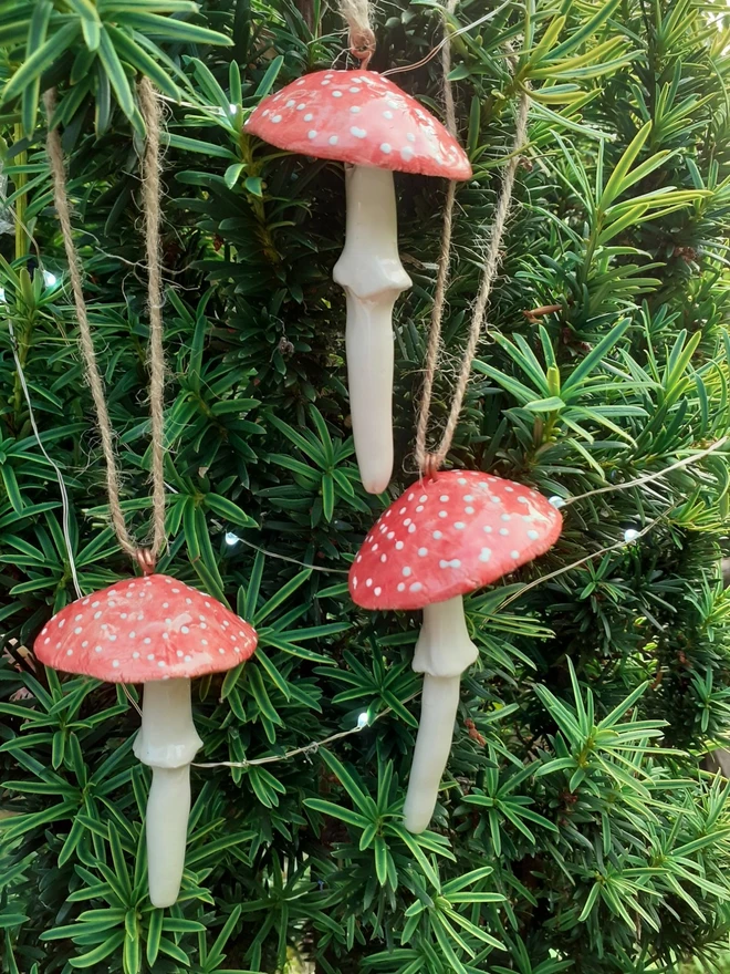 Handmade ceramic red toadstool Christmas ornaments hanging on tree