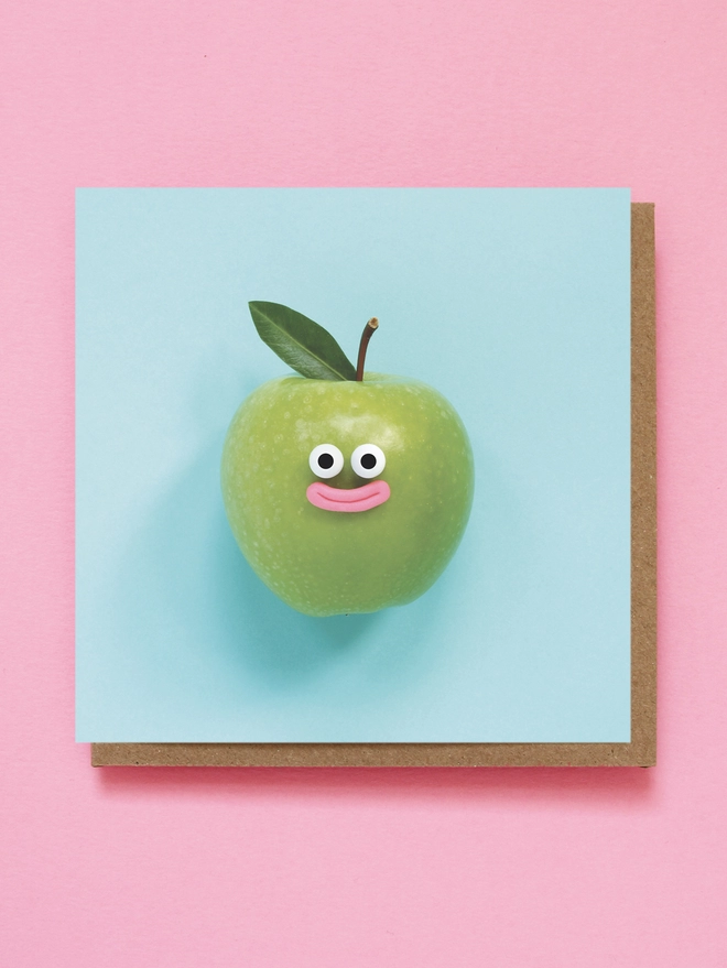 A happy green apple with a leaf. on a blue background 