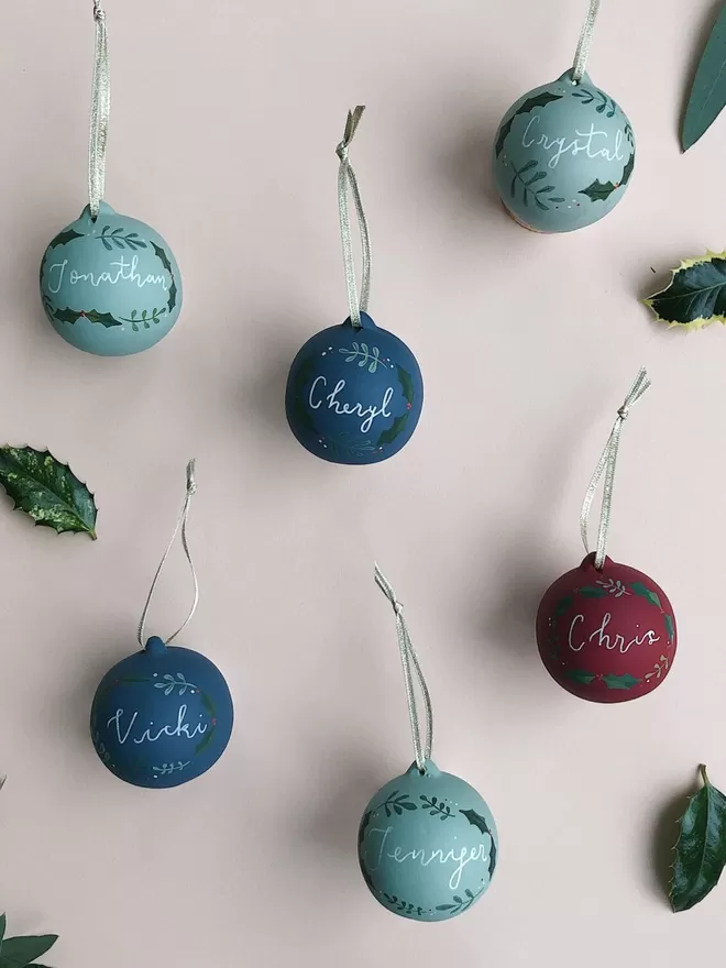 Personalised christmas baubles handpainted seen hanging on a wall