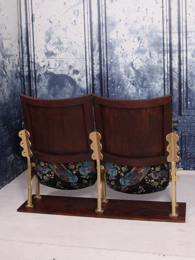Rear view of a set of two vintage cinema seats against a blue marbled wall